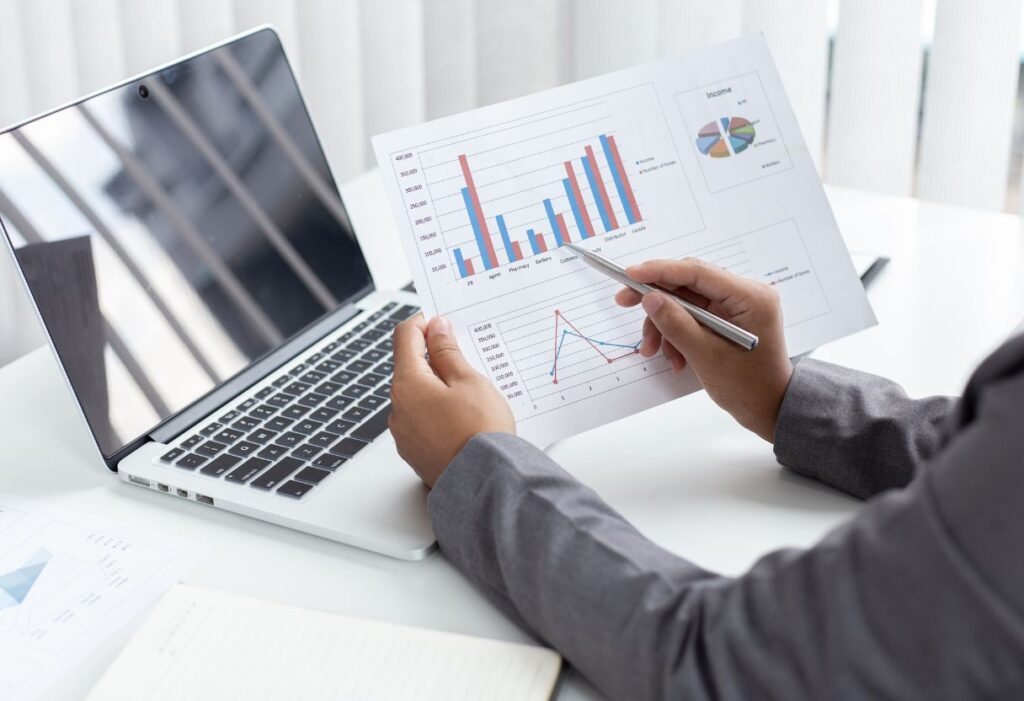 Man checking the statistics and laptop kept on a table for company audit