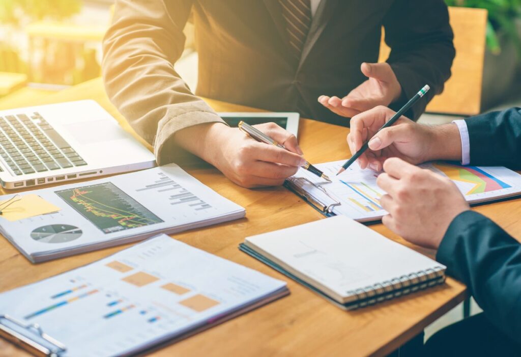 2 men discussing company growth over an office table with a laptop